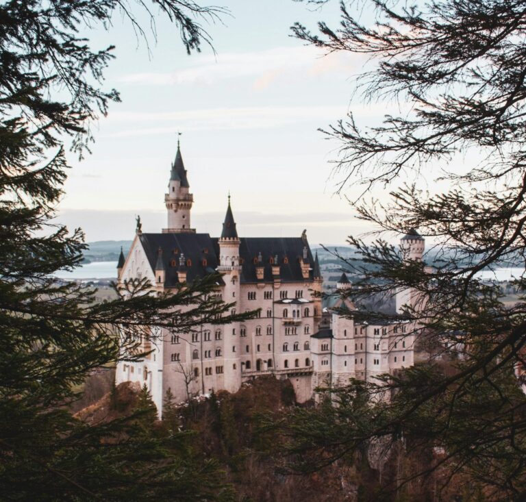Stunning view of Neuschwanstein Castle framed by trees, set in Bavarian landscape.