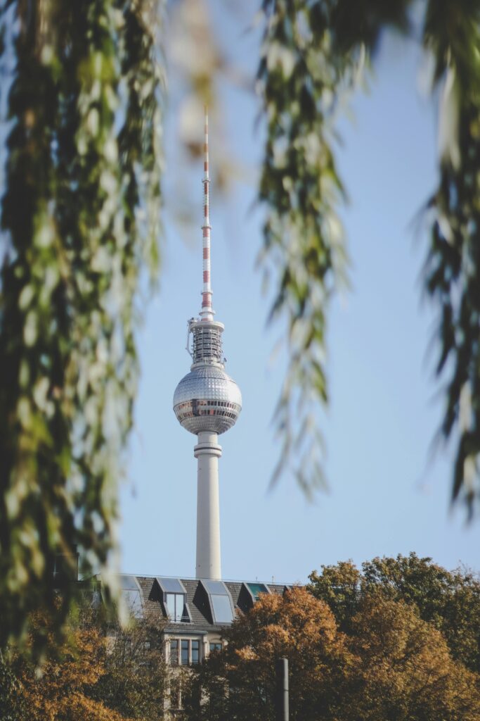 Berlin's iconic TV Tower framed by autumn leaves, captured on a clear day.